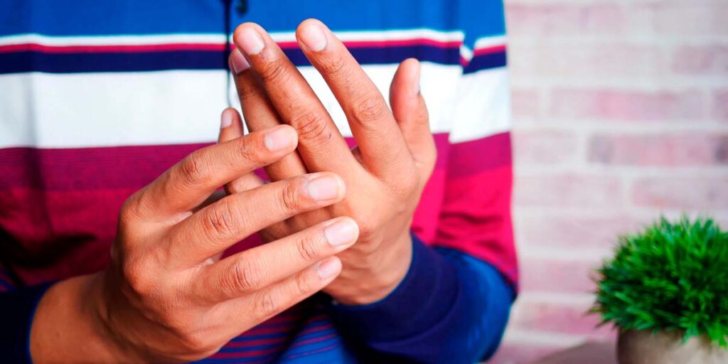 homem tocando no dedo com dor por lesão por esforço repetitivo