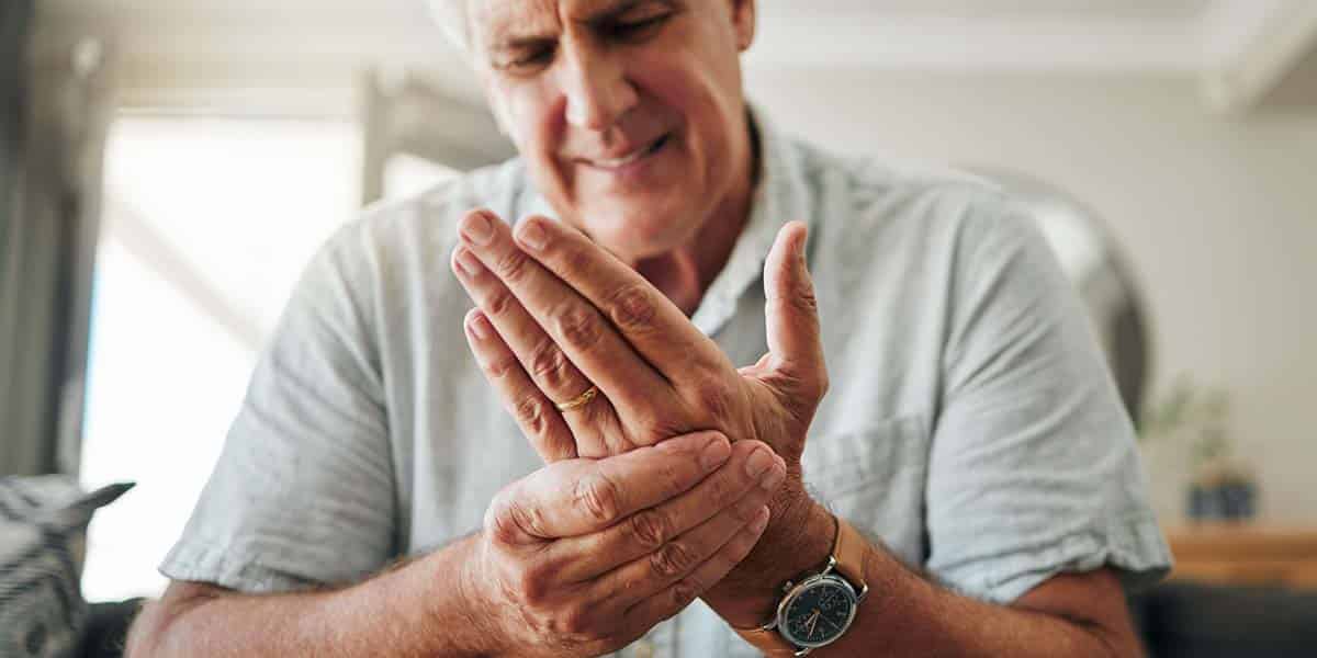 Homem massageando a mão por conta das dores nas articulações nas mãos - site Dr. Marcelo Corrêa reumatologista de Belém do Pará
