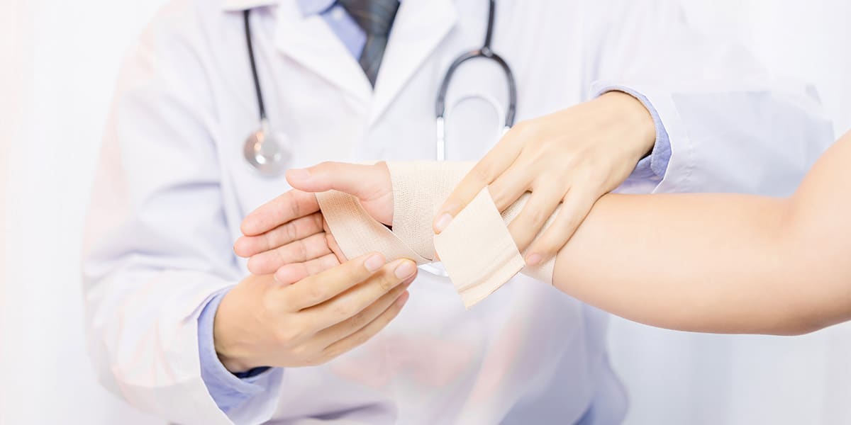 Reumatologista colocando faixa nas mãos de moça com dor na articulação das mãos site Dr. Marcelo Corrêa