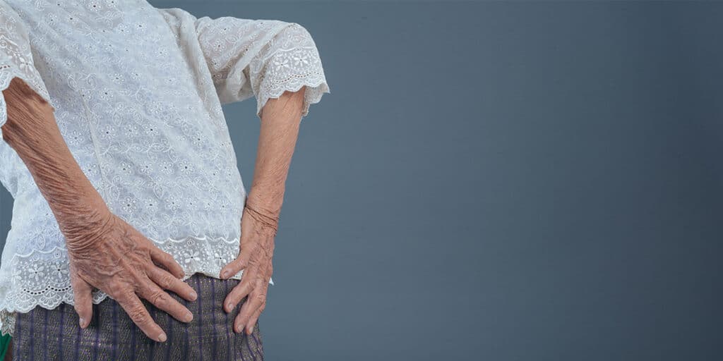 Mulher com dores nas costas por doenças reumáticas - Dr. Marcelo Reumatologista
